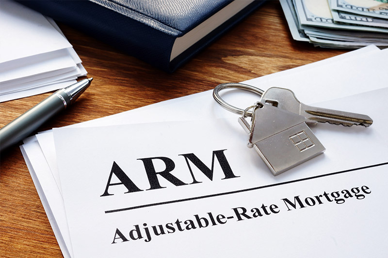 Close up of keys and paperwork that says "ARM Adjustable-Rate Mortgage"