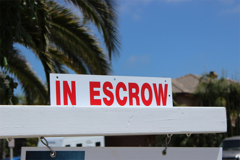 Close up of house sign that says "in escrow"